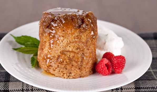 in the kitchen with stefano faita sticky apple pudding drizzled with maple syrup and served on a plate with a dollop of whipped cream and raspberries