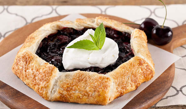 in the kitchen with stefano faita rustic cherry galette served on a baking sheet on a wooden platter with cherries on the side