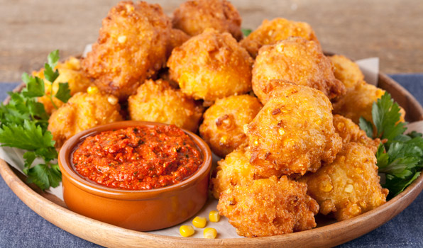 in the kitchen with stefano faita crispy corn fritters with roasted red pepper pesto served on wooden dish with parsley as garnish