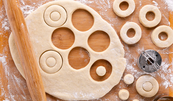 in the kitchen with stefano faita all purpose donut dough uncooked on a wooden board with portions cut out with a cookie cutter and rolling pin