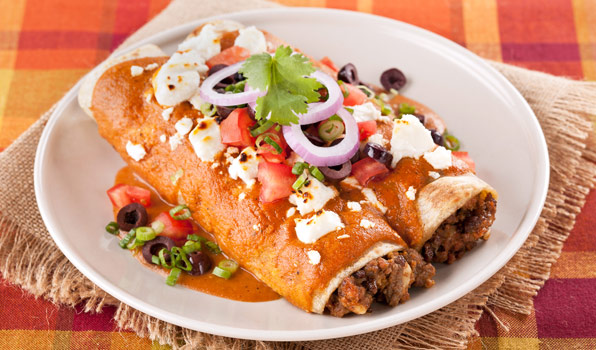 in the kitchen with stefano faita beef enchiladas topped with sliced onions, green onions, chopped tomatoes, sliced black olives, sour cream and cilantro leaves