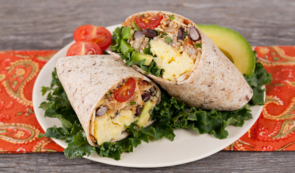 in the kitchen with stefano faita huevos rancheros burrito on a plate with a slice of avocado, cherry tomatoes and kale as decoration