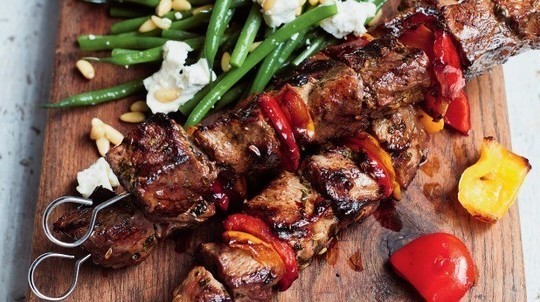 gino's italian escape grilled lamb skewers with a green bean and goat's cheese salad served on wooden cutting board