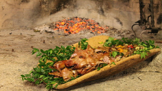 gino's italian escape roasted suckling pig with cinnamon flavoured apple sauce placed on large bowl and garnished with myrtle twigs or rosemary sprigs