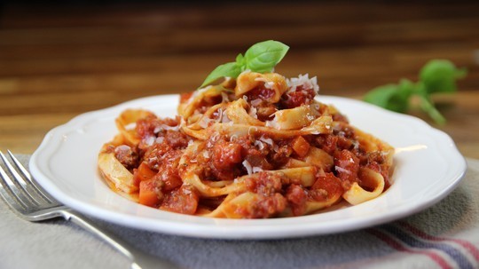 gino's italian escape classic bolognese served on plate with grated parmesan chese and basil leaf on top