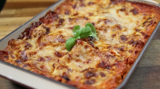 gino's italian escape traditional lasagne served on baking pan, garnished with basil leaf