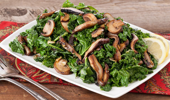 in the kitchen with stefano faita lemony greens with mushrooms served on a plate with a slice of lemon