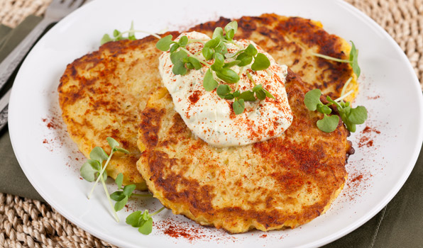 in the kitchen with stefano faita spaghetti squash latkes served on a plate with a dollop of curry yogurt dip on top