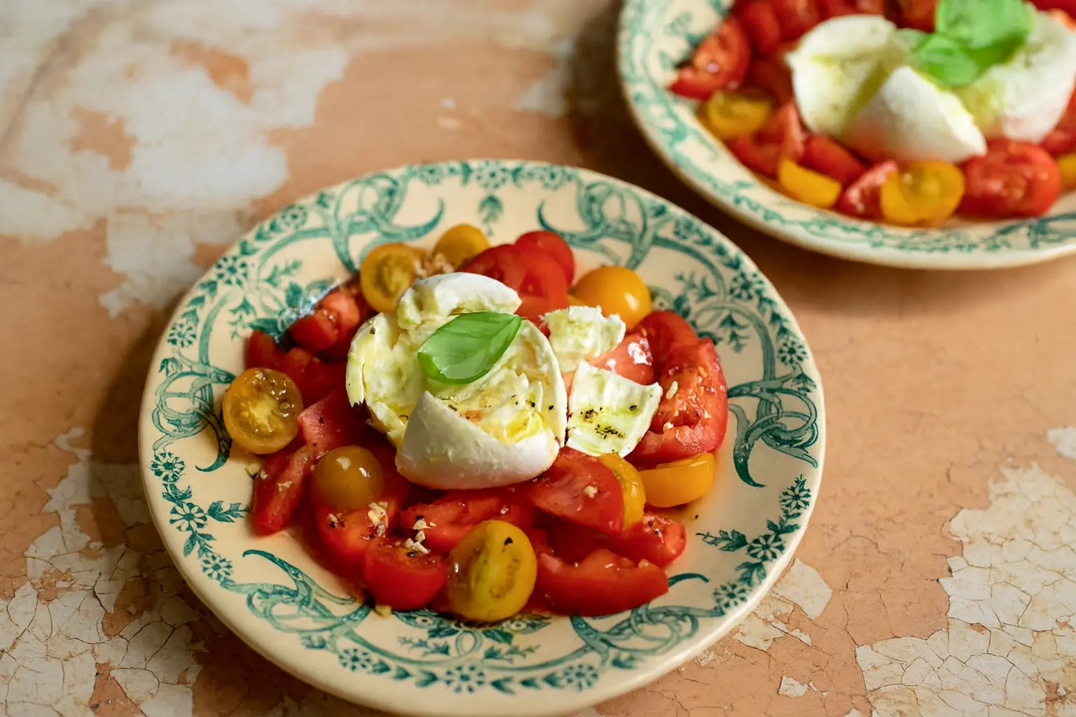 Colorful Caprese salad with ripe tomatoes, basil, garlic and buffalo mozzarella on a patterned plate